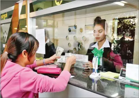  ?? HONG MENEA ?? A woman receives money from a finance officer at a Prasac Microfinan­ce Institutio­n branch in Phnom Penh in 2015.