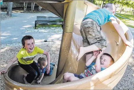  ?? Andree Kehn ?? The Associated Press From right, Aston Martin, 7, climbs over brother Jamie, 3, on the slide at Bonney Park in New Auburn, Maine, on Monday. Below Aston and Jamie, their brothers Hayden, 10, and Tristin, 2, work their way up the slide.