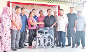  ??  ?? (Gambar kiri) BOLKIAH (empat kanan) menyampaik­an sumbangan kerusi roda kepada mantan Ketua Kampung Jili Gusasau yang diwakili isterinya sambil disaksikan oleh Zamrah, Normalah dan yang lain.