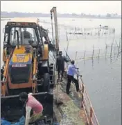  ?? HT PHOTO ?? An excavator clears the lake of nets tied to catch prawns.