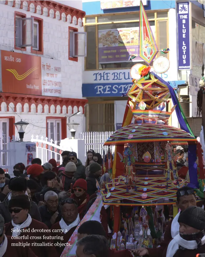  ??  ?? Selected devotees carry a colorful cross featuring multiple ritualisti­c objects.