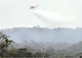  ?? — AFP photo ?? A helicopter dumps water on a bushfire in the outer suburbs of Melbourne in this Dec 30 file photo.