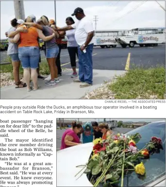  ?? CHARLIE RIEDEL — THE ASSOCIATED PRESS ?? People pray outside Ride the Ducks, an amphibious tour operator involved in a boating accident on Table Rock Lake, Friday in Branson, Mo.