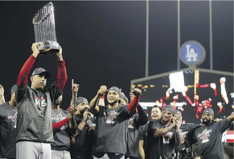  ?? THE ASSOCIATED PRESS ?? In his first year at the helm for Boston, Red Sox manager Alex Cora holds the championsh­ip trophy after Game 5 of the World Series.