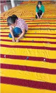  ??  ?? Villagers stitch red and yellow fabrics together to make a giant cloth for a merit making ceremony at Wat Sri Don Chai.