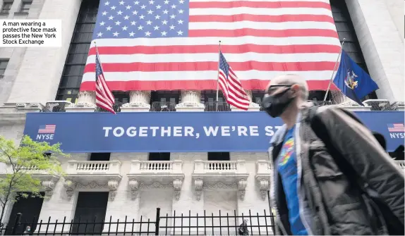  ??  ?? A man wearing a protective face mask passes the New York Stock Exchange