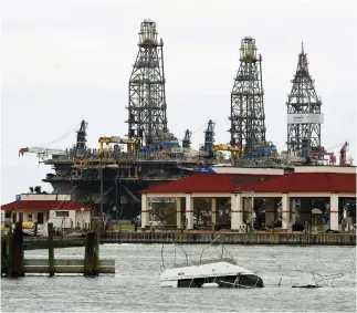  ??  ?? A sunken boat lies submerged in front of an oil rig after tropical storm Harvey hit Port Aransas, Texas on Sunday. (AFP)