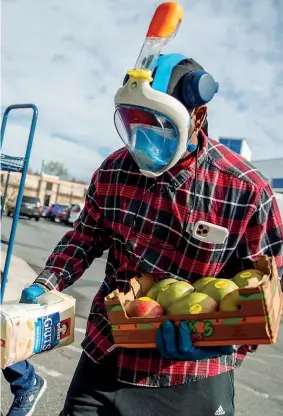  ??  ?? In maschera Un uomo carica la spesa in auto nel parcheggio di un ipermercat­o in Virginia