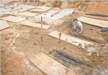  ?? 2013 PHOTO SPECIAL TO THE CLARION-LEDGER ?? Forrest Follet removes the soil from the lids of the dozens of unmarked graves on the UMMC campus.