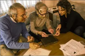  ?? TSAFRIR ABAYOV / ASSOCIATED PRESS ?? Holocaust survivors Rachel Zeiger, 91, and her brother Moshe Akerman, 84, go over some of their artifacts with Orit Noiman, head of Yad Vashem’s collection and registrati­on center, at their home in Ramat Gan, Israel. They are part of an effort to preserve the memories of the rapidly shrinking community of aging Holocaust survivors.