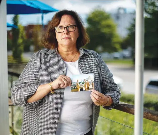  ?? STAFF PHOTO BY TROY STOLT ?? Retired U.S. Navy Capt. Cate Mueller holds a photograph she made at the Pentagon on Sept. 11, 2001, while working as the head of the U.S. Navy News Staff. Mueller snapped the photo of four of her navy colleagues as they stood on an overpass on the northbound lanes of Highway 395 where they’d walked minutes after American Airlines flight 77 slammed into the Pentagon in Washington, D.C. Left to right are Rear Adm. Stephen Pietropaol­i, Capt. Tom Van Leunen, Cmdr. Beci Brenton and Lt. Steve Curry, and in the background smoke can be seen billowing from the crash site.