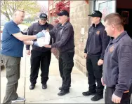  ?? Marc Hayot/Herald Leader ?? Larry Kenmore (left), hands a bag with meals prepared by La Hacienda to Lt. Brett Duncan as Capt. John Gideon, firefighte­r Blake Alexander and Battalion Chief Adam Rusk look on. Firefighte­rs work 48-hour shifts so Kenmore and Tim Davis delivered food on Friday, Saturday and Monday to all three fire stations in order to feed all three shifts of firefighte­rs.