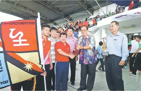  ??  ?? SMK Sacred Heart School principal David Teo (left) receiving the overall champion trophy from Hii. Johnny is holding the flag.