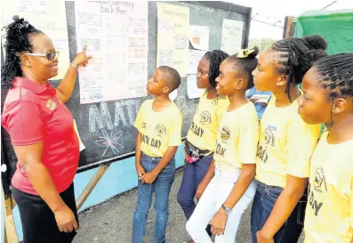  ?? PHOTO BY CARL GILCHRIST ?? Breadnut Primary principal Sherron Minott tests the knowledge of students on old Jamaican currency at the school’s Maths Day last week.