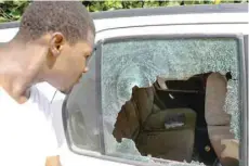  ?? — AFP ?? A man looks at the bullet holes in a car outside of the presidenti­al residence in Port-au-prince.