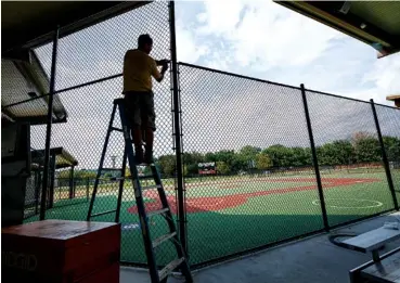  ?? STAFF PHOTO BY DOUG STRICKLAND ?? Clint Reburn installs fencing around the new Miracle Field on Thursday.