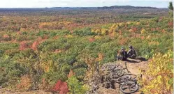  ?? STEVE MEURETT ?? Mountain bikers rest at an overlook at Levis Mound near Neillsvill­e.