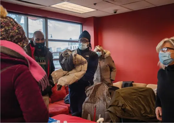  ?? AmaNDa saBga pHOTOs / BOsTON HeralD ?? WARM THOUGHTS: Barbara Foley, right, vice president of developmen­t at the Massachuse­tts Military Support Foundation, looks on as legislativ­e aide Jahleel Alieu passes a coat to a local gold star mother at an event Monday in Roxbury to provide free coats to veterans. Below, Foley, Alieu and state Rep. Chynah Tyler sort coats.