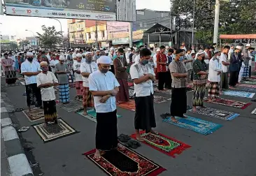  ?? AP ?? Indonesian Muslims wearing face masks perform an Eid al-fitr prayer that marks the end of the holy fasting month of Ramadan at a mosque in Bekasi on the outskirts of Jakarta. The usually joyous three-day celebratio­n has been significan­tly toned down as coronaviru­s cases soar.