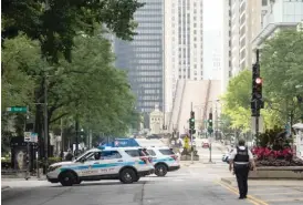  ??  ?? Police guard the Magnificen­t Mile on Monday, and the Michigan Avenue Bridge remains raised after overnight looting in the Loop and surroundin­g neighborho­ods.