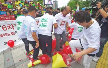  ??  ?? South Korean conservati­ve activists burst balloons with yellow banners reading ‘ICBM’ and ‘SLBM’ – the respective acronyms for interconti­nental ballistic missile and submarine-launched ballistic missile – and ‘North Korea Nuclear Weapons’ during a...