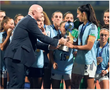  ?? AFP ?? Happy denouement: FIFA president Gianni Infantino (left) presents the winners’ trophy to Marina Artero after Spain’s 1-0 win in the final at the DY Patil Stadium in Navi Mumbai. Infantino praised India for hosting the competitio­n well.
