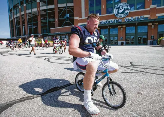  ?? Brett Coomer / Staff photograph­er ?? A 290-pound defensive end and a 5-year-old’s bike made for a cute but ultimately mismatched combinatio­n Monday. Wisconsin native J.J. Watt takes part in the Green Bay tradition of riding a fan’s bike to practice but ended up damaging it. Never fear, the youngster will be receiving a new bike courtesy of Watt.