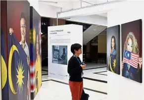  ??  ?? Getting a better look: A visitor viewing portraits of social activists Datin Paduka Marina Mahathir (left) and Siti Kasim which are among 20 portraits displayed in the Stripes and Strokes exhibition in George Town until Sept 2.