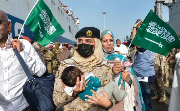  ?? AFP ?? A Saudi Navy sailor carries a child as evacuees arrive at King Faisal Navy Base in Jeddah from Sudan yesterday, following a rescue operation