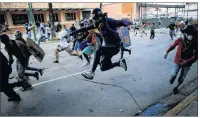  ?? "1 1)050 ?? Anti-government protesters run from advancing Venezuelan Bolivarian National Guard officers on the first day of a 48-hour general strike in protest of government plans to rewrite the constituti­on, in Caracas, Venezuela, Wednesday.