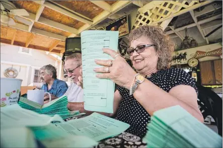  ?? Photograph­s by Tomas Ovalle For The Times ?? MARY GONZALES GOMEZ, right, with husband Raul Gomez and other members of the Kings County Latino Roundtable, folds voter guides in the Central Valley city of Corcoran last month. Tuesday’s primary felt quieter than those in previous years, they said.