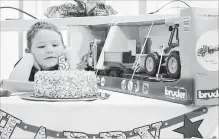  ?? RICHARD HUTTON
METROLAND ?? Alexzander Carriere eyes a birthday cake that was just for him at an event marking the fifth anniversar­y of St. Catharines hospital.