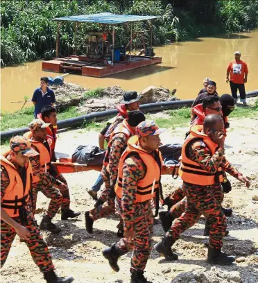  ??  ?? Tragic end: The fire and rescue team carrying the body of Muhammad Ikhwan Mohd Ridwan, the sixth of seven children who were swept away by the rapids while fishing in Sungai Selangor.