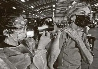  ?? Eddie Seal / Bloomberg ?? A health care worker administer­s a dose of the Moderna COVID-19 vaccinatio­n at a drive-thru clinic at the Richard M. Borchard Regional Fairground­s in Robstown.