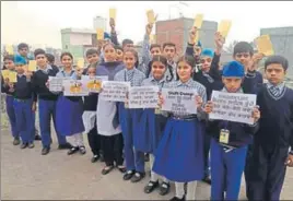  ?? HT PHOTO ?? School students carrying playcards with an appeal to the chief minister to relocate the Bhagtanwal­a garbage dump on the outskirts of Amritsar on Wednesday.