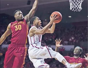  ?? J Pat Carter Getty I mages ?? I SAIAH COUSINS of Oklahoma slips past Deonte Burton of Iowa State for a basket in the second half.