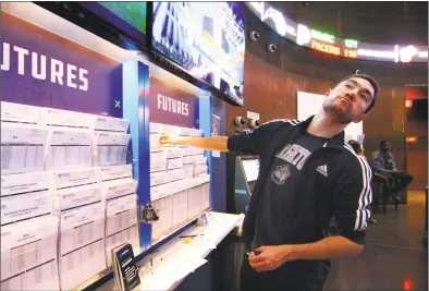  ?? Christian Abraham / Hearst Connecticu­t Media ?? While checking the futures out, Michael Brandon, of Stamford, pauses to see the Texas Tech NCAA basketball game during a day at FanDuel Sportsbook at the Meadowland­s in East Rutherford, N.J., on March 29. Connecticu­t is considerin­g legalizing sports betting, leaning toward a New Jersey model, where people can bet in person at casinos and racetracks, as well as online.