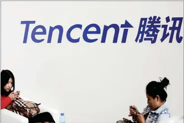  ?? PHOTO: REUTERS ?? Visitors use their smartphone­s underneath the logo of Tencent. China’s largest social network and gaming company posted a 61 percent jump in net income to 23.3 billion yuan in the three months ended March.