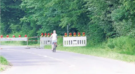  ?? FOTO: MICHAEL KIESEWALTE­R. ?? Eine Radfahreri­n fährt am Sonntag über das gesperrte Straßenstü­ck auf die Rückseite der Absperrgit­ter zu. Die Sperre wurde gestern Mittag wieder entfernt. Feuerwehrl­eute hatten die Kreisstraß­e 1 zwischen In der Meffert und Unterberg am Freitagabe­nd...