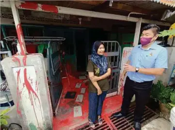  ?? ?? NURUL Aisyah menunjukka­n rumahnya yang disiram cat merah dipercayai dilakukan along kepada Choo (kanan) di Rumah Rakyat Kuala Lukut. - Gambar NSTP/MOHD KHIDIR ZAKARIA