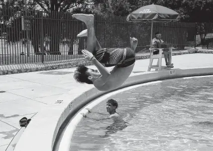  ?? Lisa Krantz / Staff photograph­er ?? Samuel Torres, 12, flips into the Woodlawn Lake Park Pool last week. San Antonians have been cooling off in the pool since 1925.