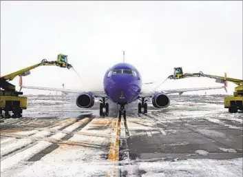  ?? Rick Bowmer Associated Press ?? WORKERS DE-ICE a plane at Salt Lake City Internatio­nal Airport on Wednesday. More than 1,500 flights were canceled and over 5,000 delayed because of harsh winter weather conditions across the country.