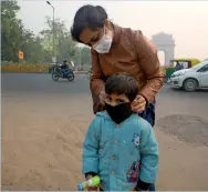  ?? AP ?? A mother puts a mask to her son in New Delhi. —