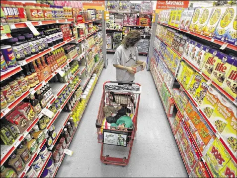  ?? TONY GUTIERREZ / ASSOCIATED PRESS 2010 ?? Alicia Ortiz shops through the cereal aisle as her daughter Aaliyah catches a short nap in the shopping cart at a Family Dollar store in Waco, Texas. Up and down supermarke­t aisles, rows of perfectly placed products reflect calculated deliberati­ons...