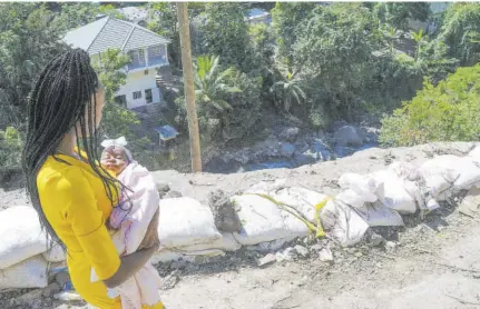  ??  ?? This new mother from Mavis Bank carefully passes the hazardous section of the Gordon Town Road to get her her baby to Kintyre New Testament Church for christenin­g on Sunday.