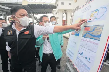  ?? SATRABHAYA PORNPROM ?? Man with a plan
Bangkok governor Pol Gen Aswin Kwanmuang inspects flood drainage preparatio­ns at the Khlong Lat Pho floodgate in Samut Prakan as the navy prepares to supply water-propelling boats to speed up drainage of water into the sea.