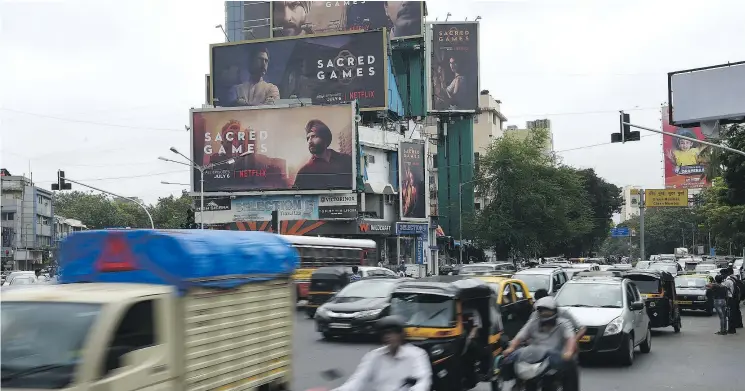  ?? GETTY IMAGES ?? Indian commuters travel past large billboards for Sacred Games, the Indian series on Netflix, which has enthralled audiences in this country of 1.3 billion.