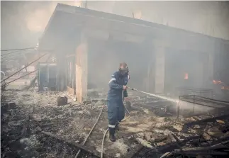  ??  ?? A firefighte­r tries to douse a blaze that destroyed several homes in the coastal town of Kineta, west of Athens, yesterday, and ravaged a large expanse of forestland. Firefighte­rs’ efforts were hampered by strong winds.