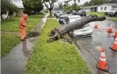  ?? BRITTANY MURRAY / THE ORANGE COUNTY REGISTER ?? Crews clean up after a tree fell on a car in Long Beach, Calif., on Monday. A powerful storm turned hillsides into rivers of mud, leading to evacuation orders in some areas.