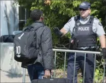  ?? PAUL CHIASSON, THE CANADIAN PRESS ?? An asylum seeker, claiming to be from Eritrea, is questioned by an RCMP officer on the border near Champlain, N.Y.